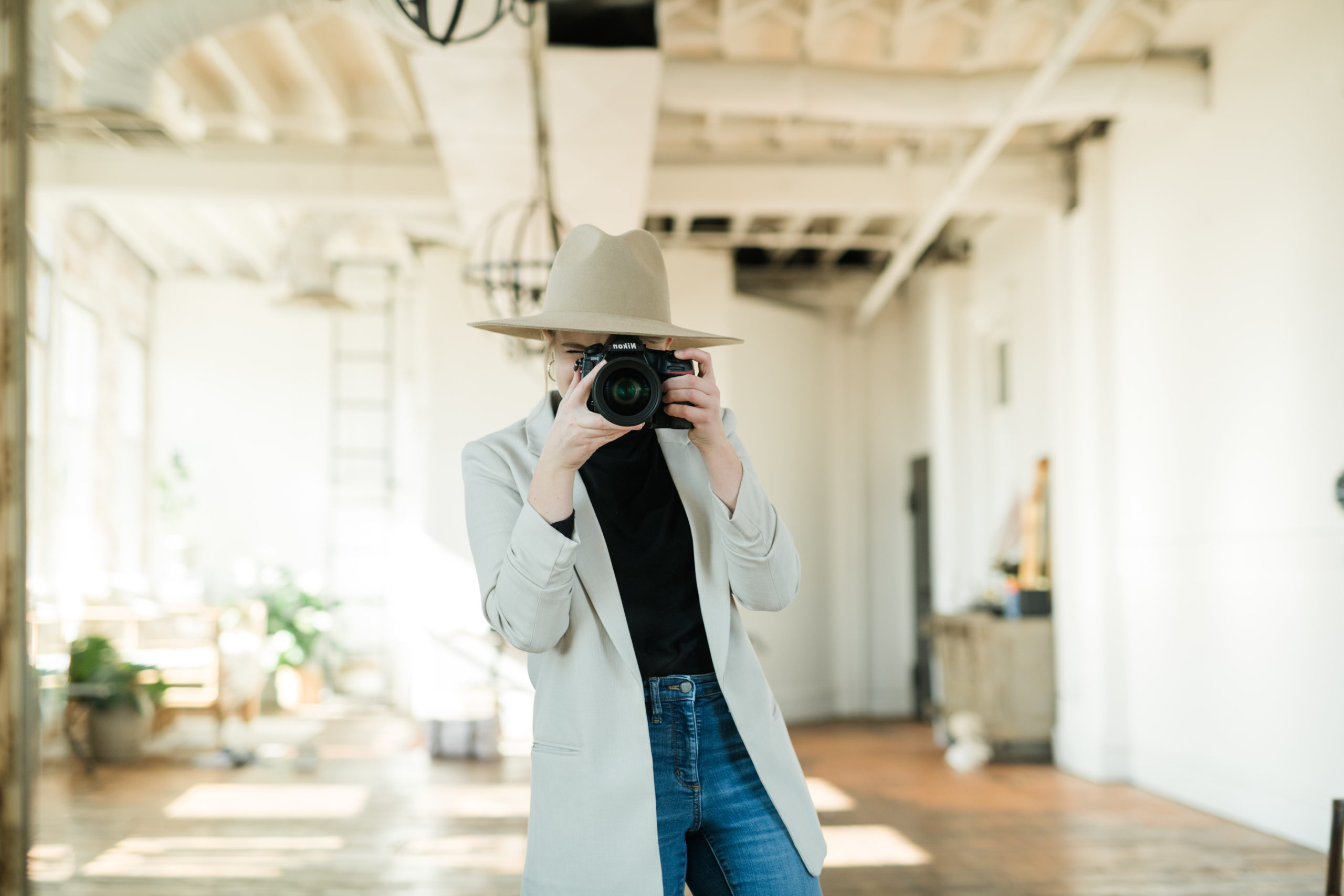 Woman brand photographer holding camera in front of face